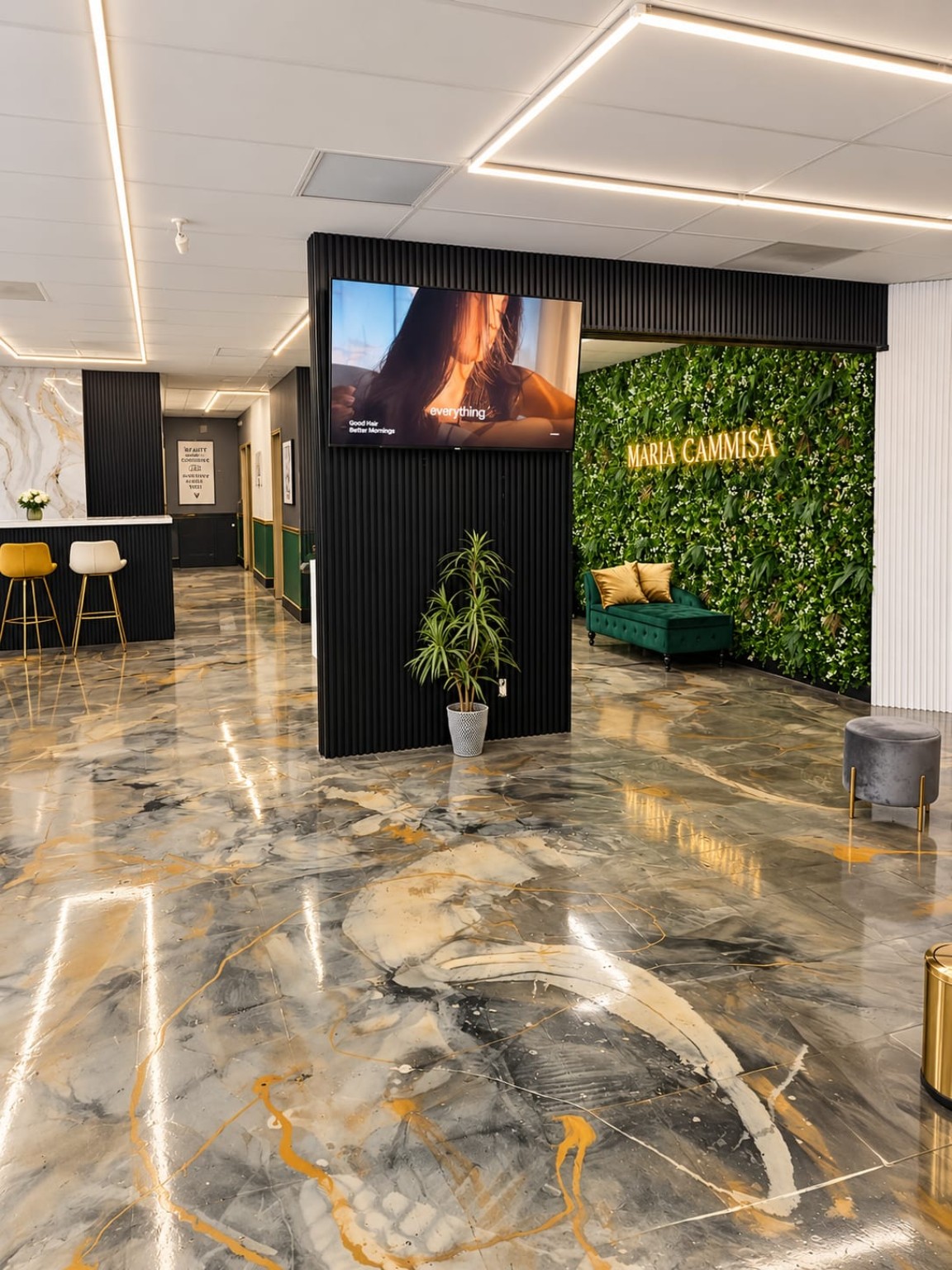The boutique lounge with green seating and the Maria Cammisa feature wall